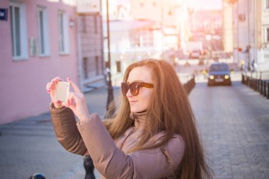 Genç, güzel bir kadın kendini akıllı telefonuna özçekim yapıyor.