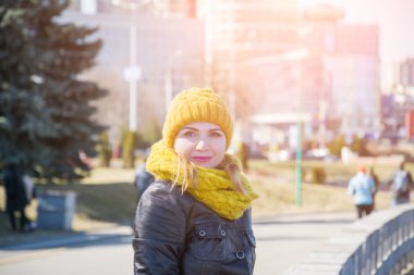 Portre sarışın kıvırcık oynak hipster kadının sokakta, şehir parkları gülümseyerek kameraya, seyir açık yakından. Giydiği beyaz kazak, sarı kış şapka, sarf, eldiven modeli.
