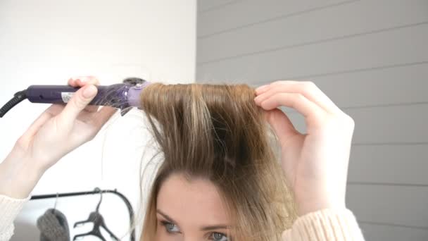 Portret jonge blonde vrouw, terwijl curling haar met behulp van haar Tang in beautystudio — Stockvideo