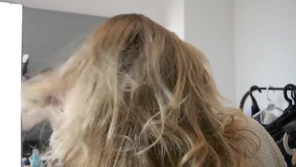 Молода блондинка жінка отримує зачіску довге волосся з залізом в перукарський салон — стокове відео