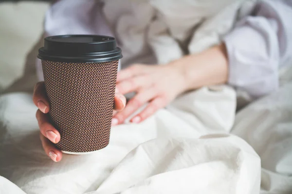 Primer plano de la mujer con la bebida caliente de la mañana Copa en la cama en casa — Foto de Stock