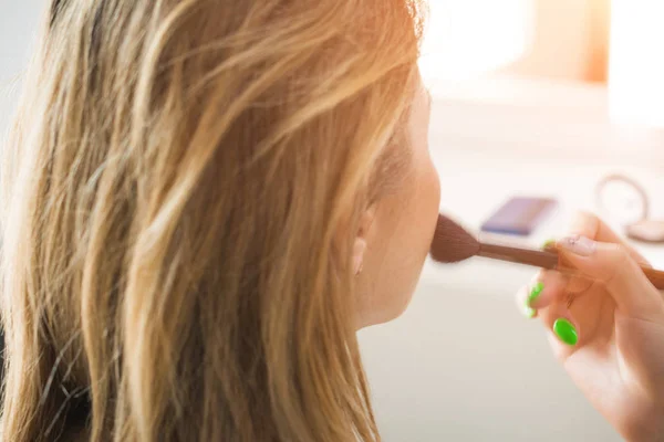 Ung kvinde anvender make-up, mens du bruger en pulverbørste - Stock-foto