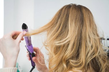 Orta yaşlı olgun kadın ısıtmalı Curling maşa ile sabah saçlarını yapıyor