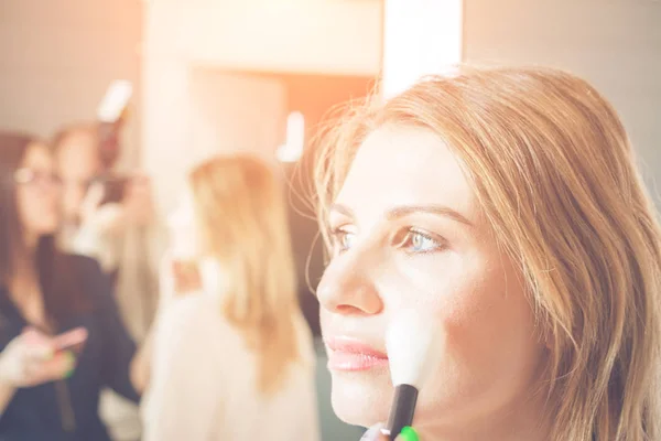 Ung, smuk blondine kvinde sat på make-up i en skønhedssalon - Stock-foto