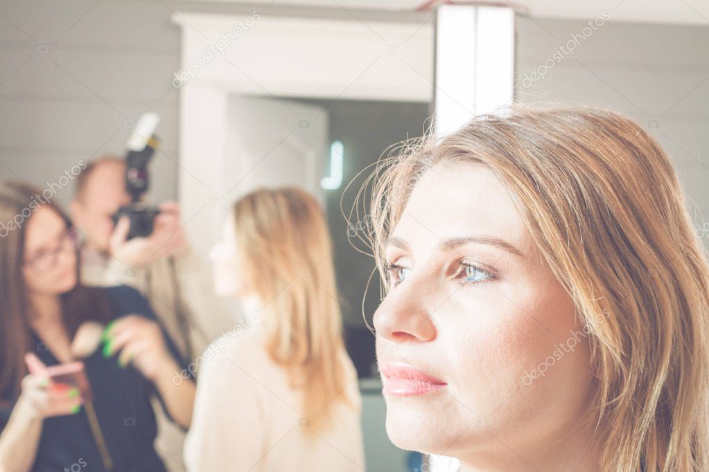 young, beautiful blonde woman put on make-up in a beauty salon