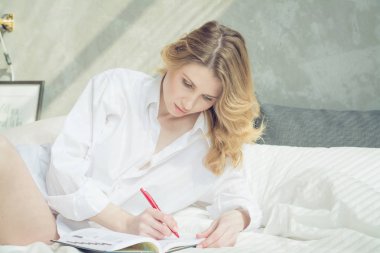 Sarışın kadın yatak odasında bir kitap yazma