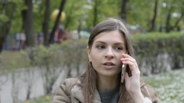 Chica atractiva hablando emocionalmente en la naturaleza en un parque de la ciudad — Vídeos de Stock