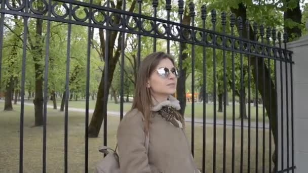 穿着夹克和太阳镜的漂亮女孩在公园里抽烟 — 图库视频影像