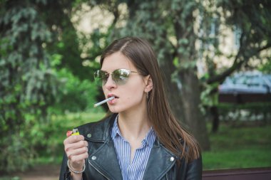 ağzında bir sigara ile parkta güzel bir genç kadının portresi
