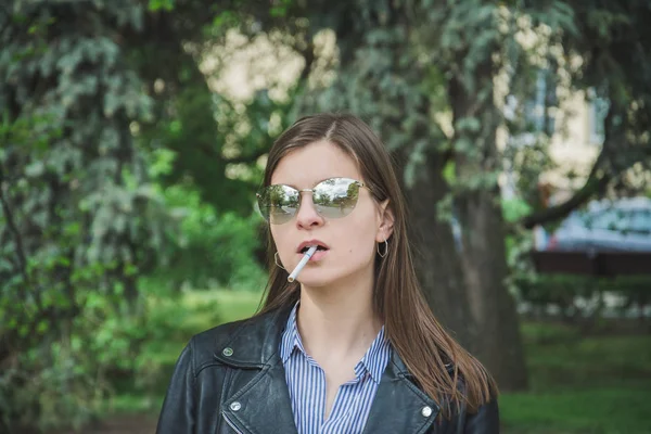그녀의 입에 담배와 공원에서 아름다운 젊은 여자의 초상화 — 스톡 사진