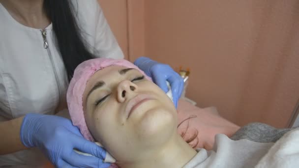 Cosmetologist rubs skin of face to female patient an intensive procedure — Stock Video