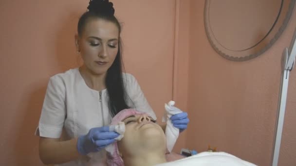 Genç kadın profesyonel güzellik uzmanı ve dermatolog kliniğinde kanepede yatıyor. Kadın doktor cilt yüz üzerinde temizler. Güzellik ve spa sanayi kavramı — Stok video