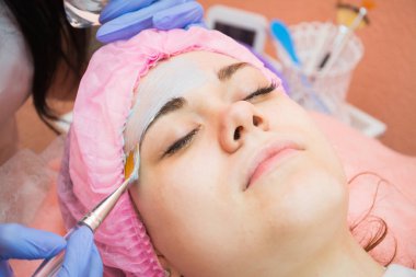 Genç bir kızın yüzüne temizlik maskesi uygulama prosedürü