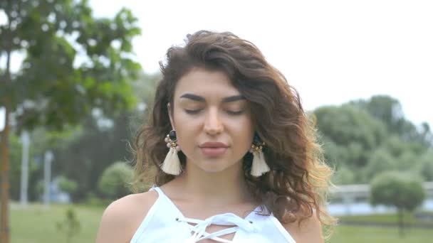 Retrato de uma bela jovem com cabelo encaracolado no parque — Vídeo de Stock
