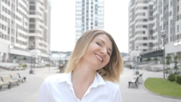 Fille regarde dans la caméra et sourit portrait en gros plan sur le fond d'un complexe résidentiel — Video