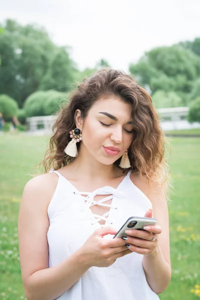 Schönes Mädchen mit lockigem Haar schickt SMS an ihren Freund — Stockfoto