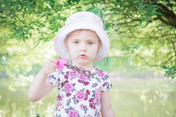 Een klein meisje blazen van zeepbellen in zomer park — Stockfoto