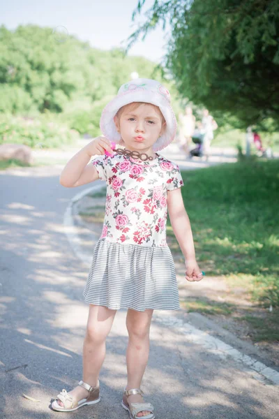 Little girl blowing soap bubbles in summer park — Stock Photo, Image