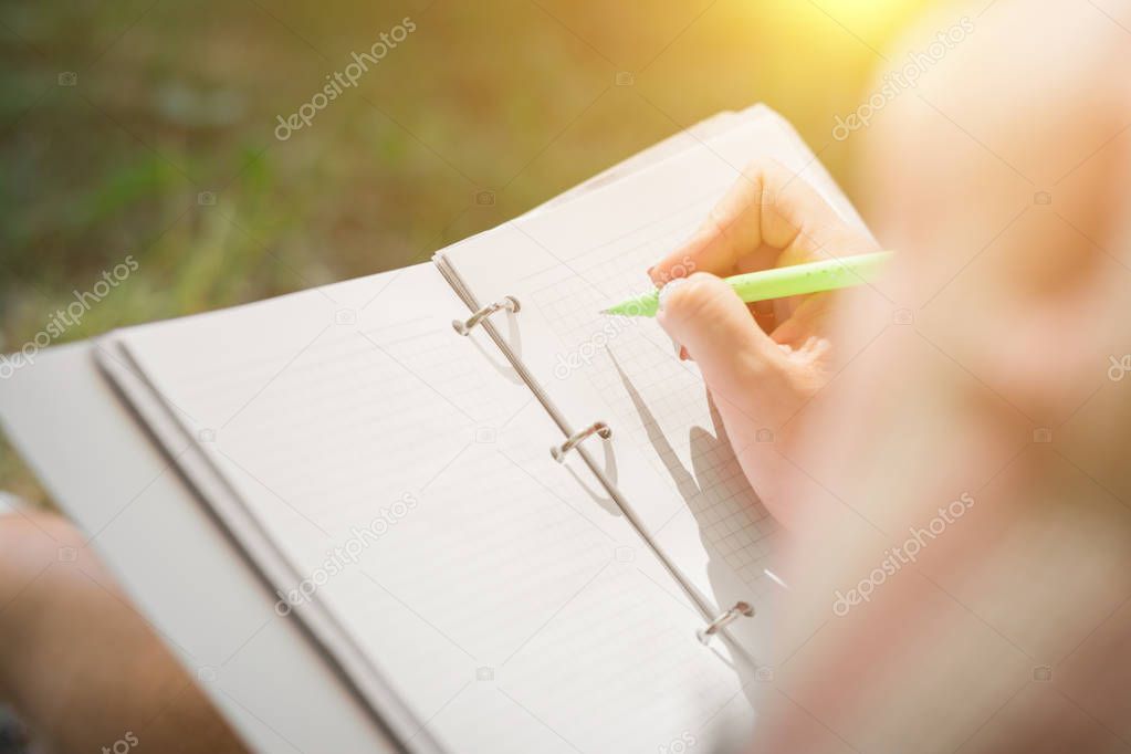 girls hands with pen writing on notebook