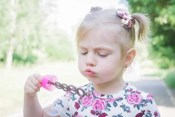 Una niña soplando burbujas de jabón en el parque de verano — Foto de Stock