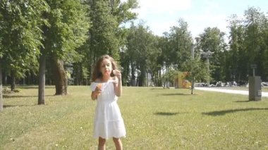 Yeşil bir Park hd görüntüleri sabun kabarcıkları ile oynarken farklı renklerde gözleri ile küçük bir sevimli kız