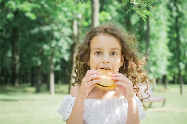 Bambina mangiare hamburger o cheeseburger all'aperto — Foto Stock