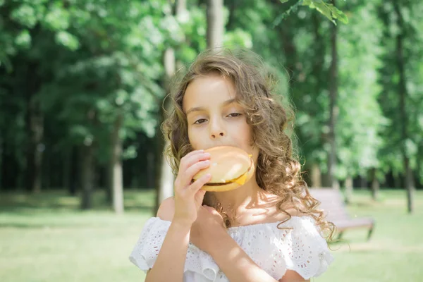 Bambino che mangia un hamburger o un cheeseburger — Foto Stock