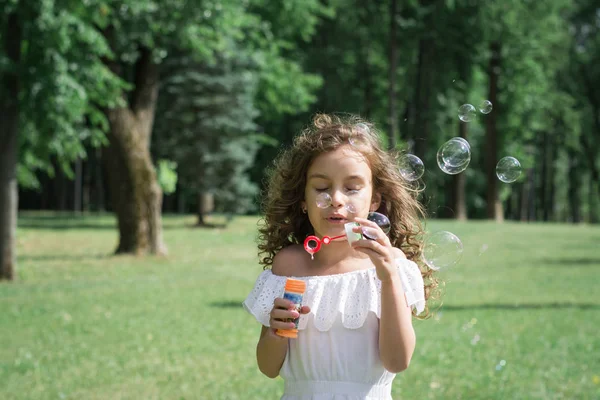 Mujer niño soplando burbujas de jabón al aire libre — Foto de Stock