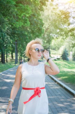 Yazlık elbiseli şık kız bir yaz parkında bir fotoğrafçı için poz