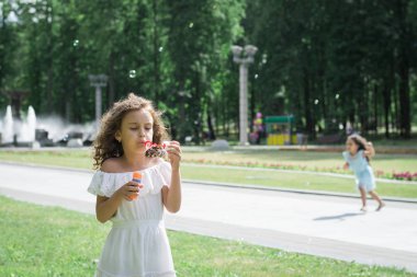 Küçük bir kız sabun köpüğü üflüyor.