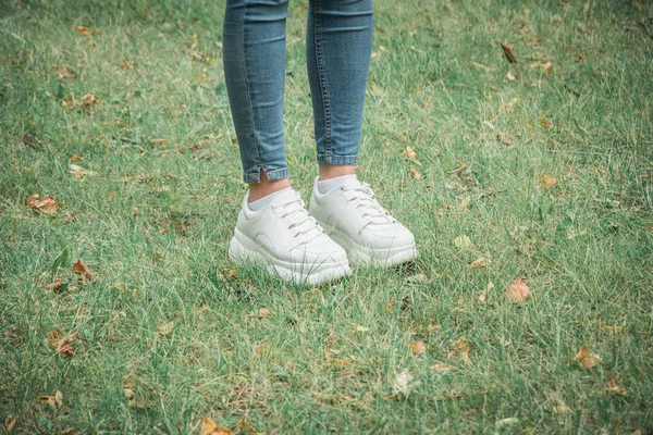 Nahaufnahme weiblicher Füße in Turnschuhen auf grünem Gras im Park — Stockfoto