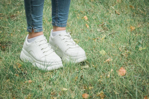 Close-up vrouwelijke voeten in Sneakers op groen gras in het Park — Stockfoto