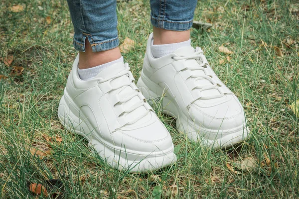 Close-up vrouwelijke voeten in Sneakers op groen gras in het Park — Stockfoto