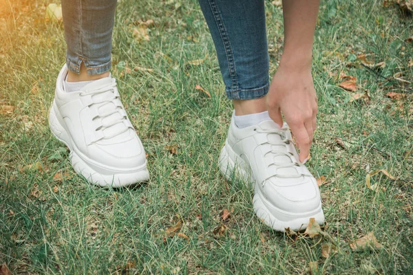 Vrouwelijke voeten in jeans en witte sportschoenen — Stockfoto