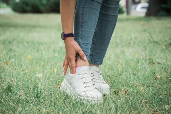 Pieds féminins en jeans et chaussures de sport blanches — Photo