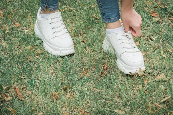 Gros plan jambes de femme vêtue de jeans et baskets marchent sur l'herbe . — Photo