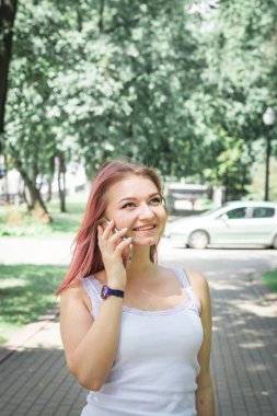 Cep telefonu kullanan güzel genç kadın, sokakta yaz saatinde açık havada