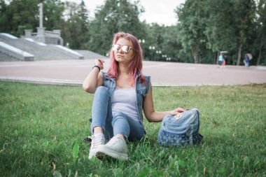 Akıllı hipster öğrenci yeşil çim üzerinde oturan