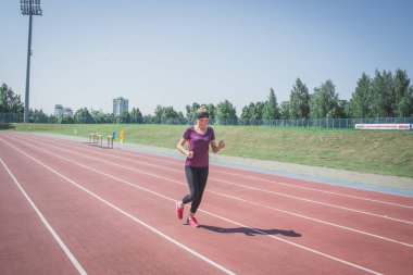Güneşli sabah sırasında Stadyumu yolda çalışan genç kadın