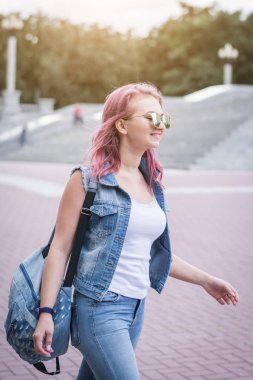 Promosyon arka plan yakın kentsel ortamda yürüyüş şık sırt çantası ile çekici hipster öğrenci