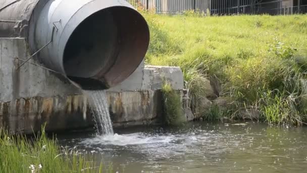 Large industrial pipe discharges water into a pond — Stock Video