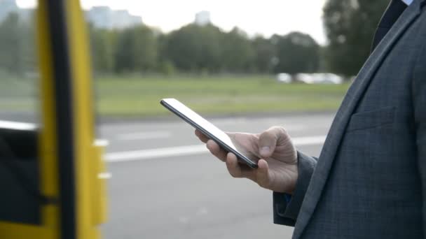 Vue rapprochée des mains de l'homme d'affaires utilisent le téléphone près de la route, appelle un taxi — Video