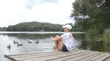 Gölde iki kuğu ve ördek besleyen kadın