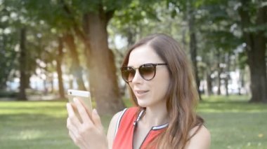 genç kız bir yaz parkında bir görüntülü arama konuşuyor