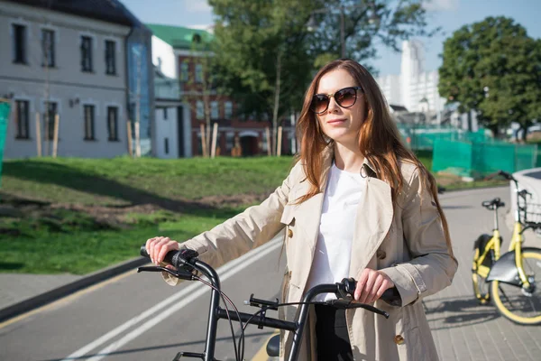 Beautiful red head woman on bike in the city — Stock Photo, Image