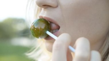 Kırmızı dudakları olan bir kadın tatlı bir lolipop chups yalıyor ve şeker hd stok görüntüleri sahiptir