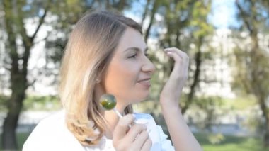 Kırmızı ruj ile Kadın yüz ve dudaklar büyük pembe yuvarlak lolipop emmek