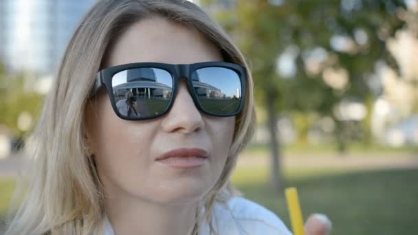 Mladá dívka nosí sluneční brýle, usrkávala koktejl s slámou — Stock video