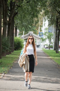 Yaz güneşli bir hayat tarzı. Sokakta yürüyen genç ve şık bir hipster kadın.