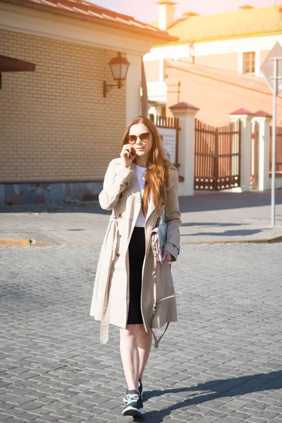 Mujer de moda caminando y hablando en el teléfono móvil en una calle de la ciudad — Foto de Stock